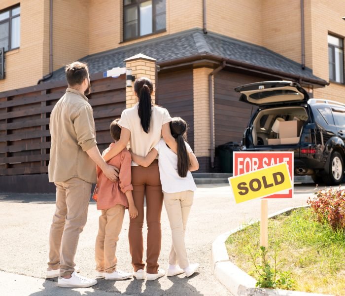 Family embracing each other in front of new house
